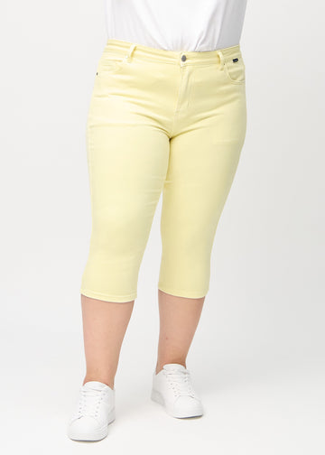 Lysegule skinny capris, modelnavn Lemonades, som sidder tæt til benet på en plus-size model, set forfra.