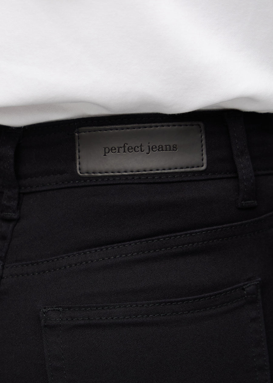 Nahaufnahme von schwarzem Jeansmaterial mit Perfect Jeans Lederpatch hinten am Bund.