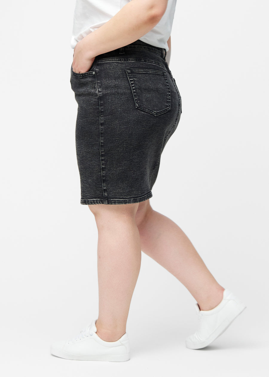 Mørkegrå, tætsiddende og knælang denimnederdel set fra siden på plus-size model.