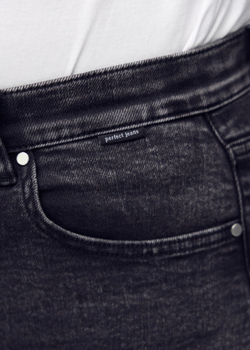 Forlommen på et par mørkegrå denim jeans, hvor man kan se logoet på en plus-size model.