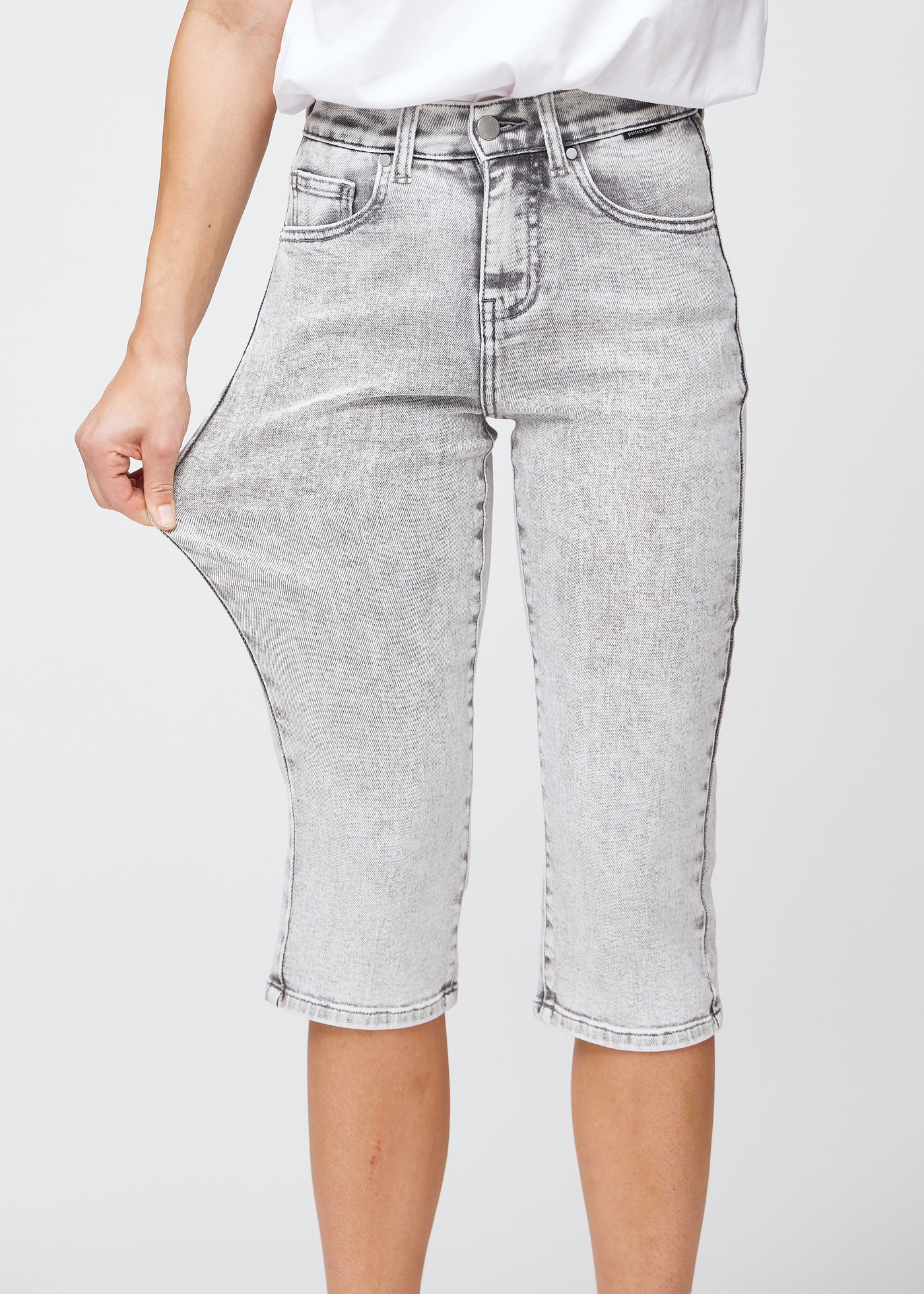 Model strækker caprisene ved låret for at vise stretch.