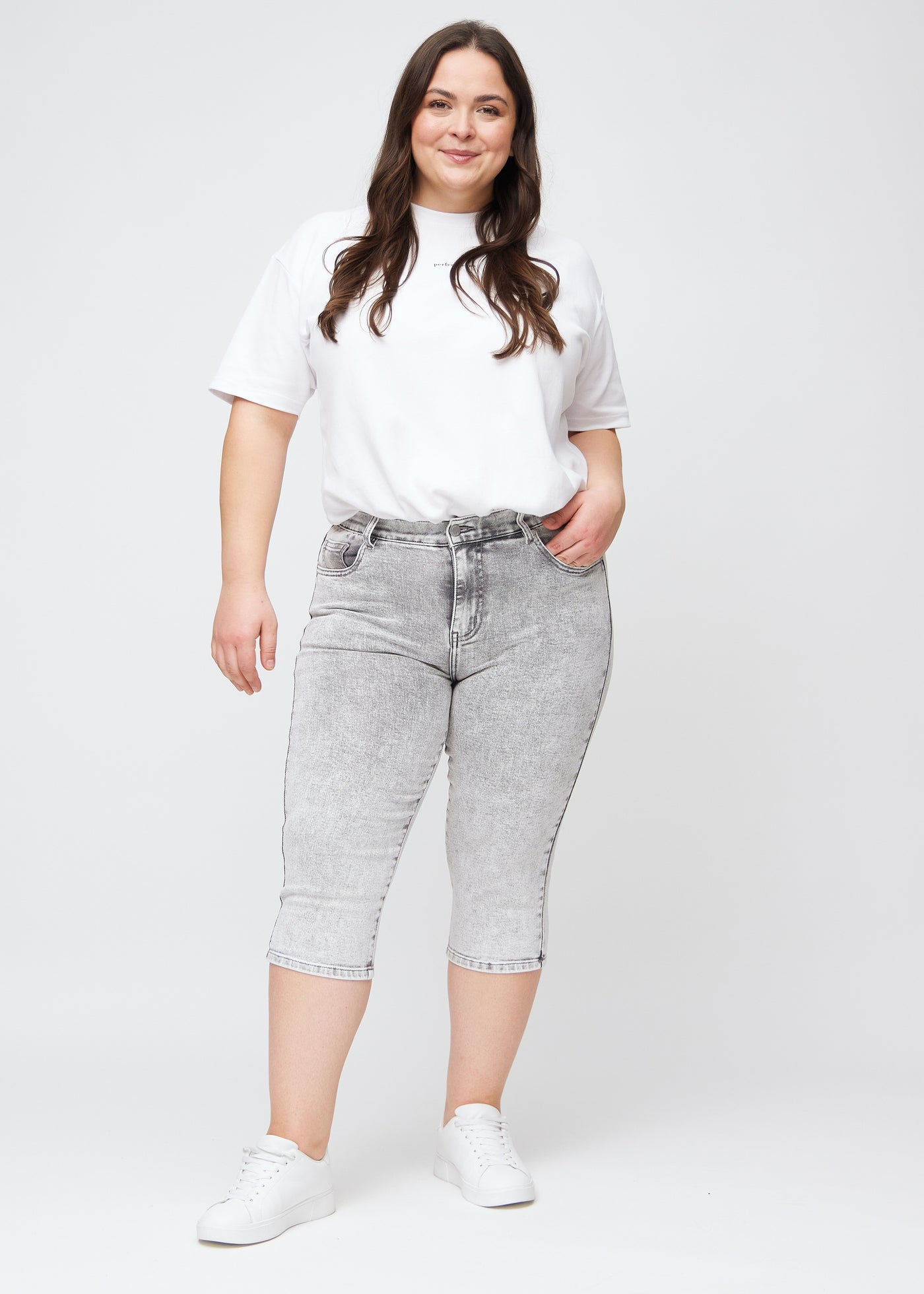 Fuldt billede af plus-size model i lysegrå denim slim capris.