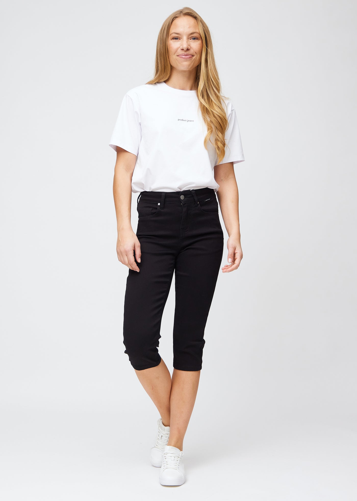 Fuldt billede af model iført sorte slim capris.