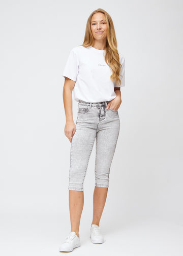 Model går ind i billedet, strækker i sine capris, viser dem frem ved at dreje rundt, og forlader derefter billedet.