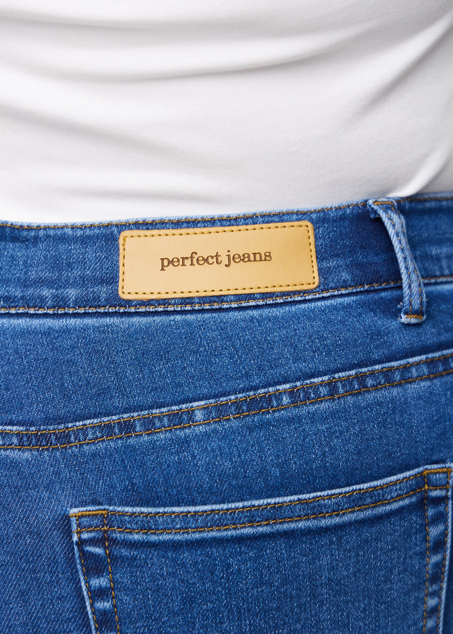 Nahaufnahme von dunkelblauem Denim mit Perfect Jeans Lederpatch hinten am Bund auf einem Plus-Size-Modell.