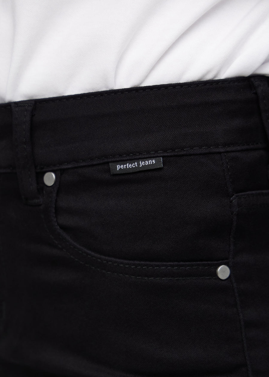 Nærbillede af sort jeansmateriale med Perfect Jeans logoetiket ved forlommekanten.