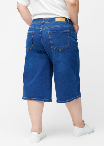 Løse, mørkeblå denim capris i farven Oceans set bagfra på plus-size model, så pasform og længde kan ses.