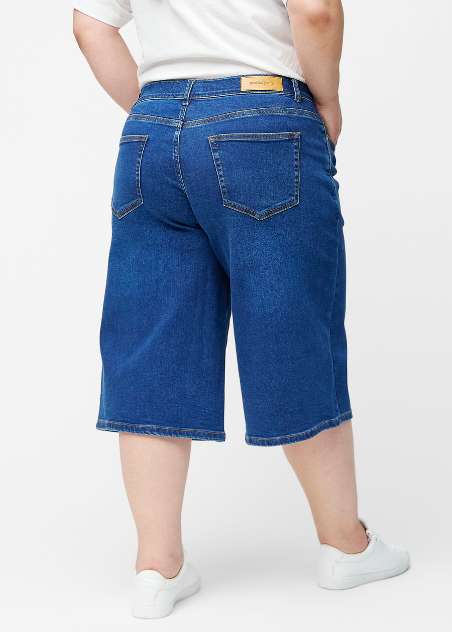 Løse, mørkeblå denim capris i farven Oceans set bagfra på plus-size model, så pasform og længde kan ses.