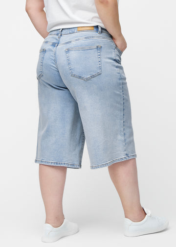 Lockere, hellblaue Denim-Capris in der Farbe Waves von hinten am Plus-Size-Model gesehen, sodass Passform und Länge sichtbar sind.