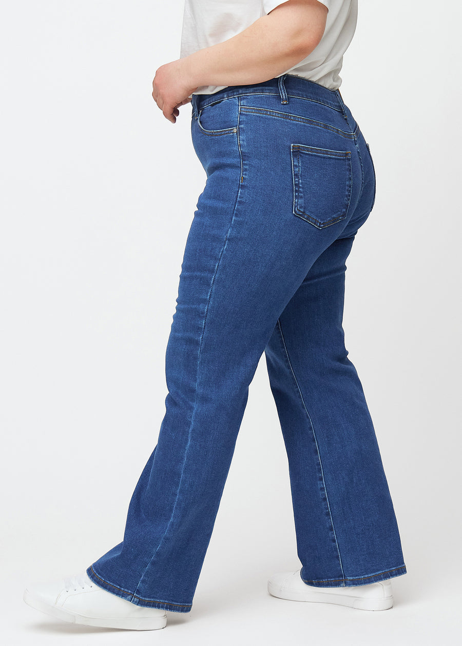 Dunkelblaue Mid-Rise-Bootcut-Jeans in der Farbe Oceans. Seitenansicht an einem Plus-Size-Model.