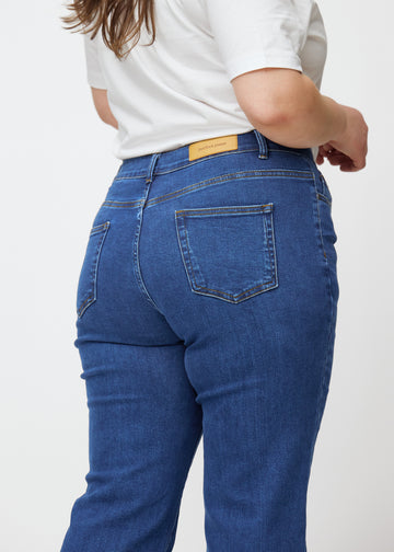 Dunkelblaue Mid-Rise-Bootcut-Jeans in der Farbe Oceans. Nahaufnahme der Rückseite an einem Plus-Size-Model, um Details zu zeigen.
