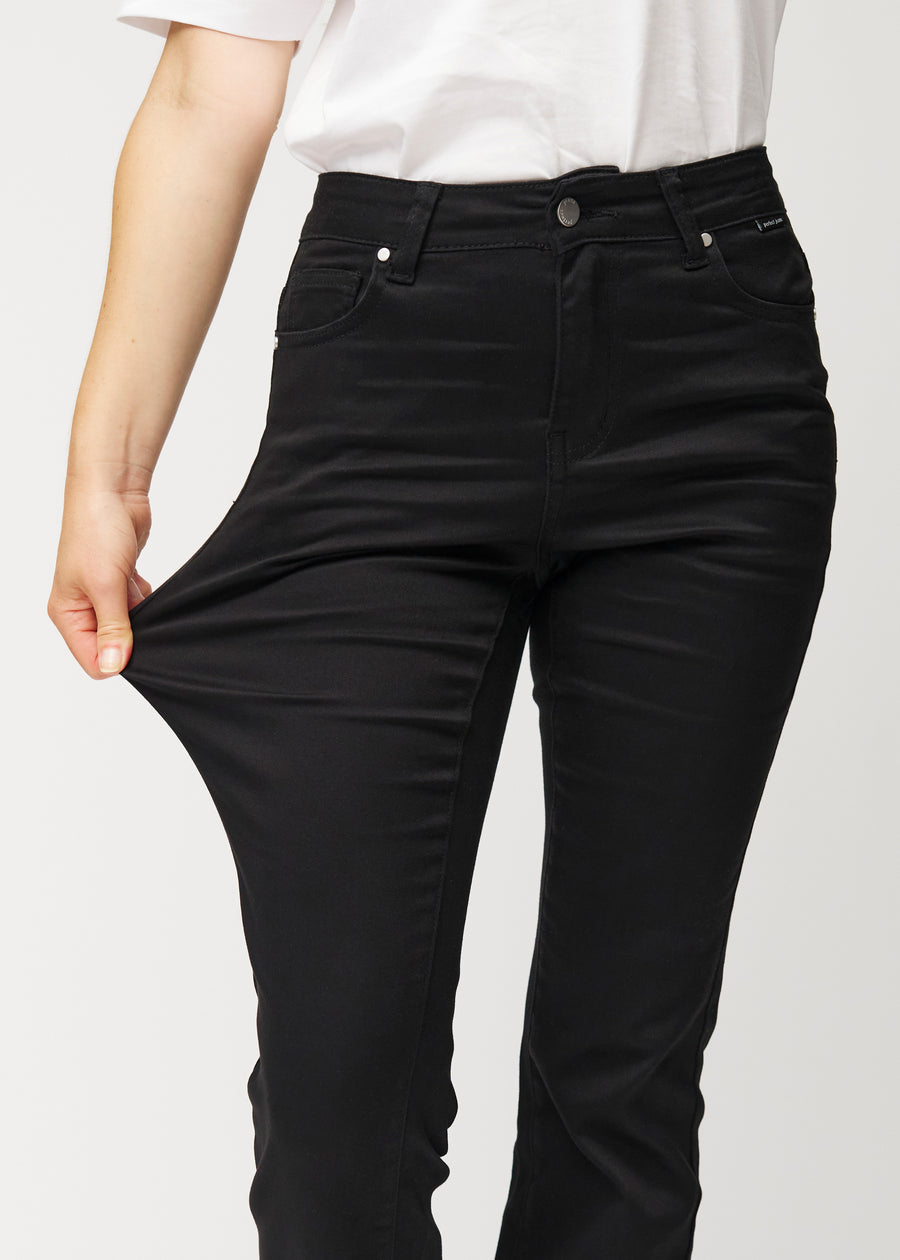 Schwarze Mid-Rise-Bootcut-Jeans in der Farbe Ravens. Ein Model zieht am Jeansstoff am Oberschenkel, um den Stretch zu zeigen.