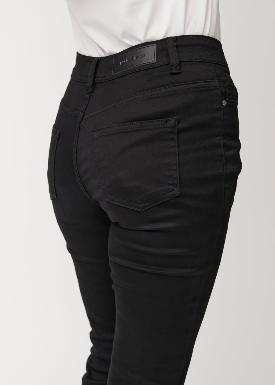 Schwarze Mid-Rise-Bootcut-Jeans in der Farbe Ravens. Nahaufnahme der Rückseite an einem Model, um Details zu zeigen.