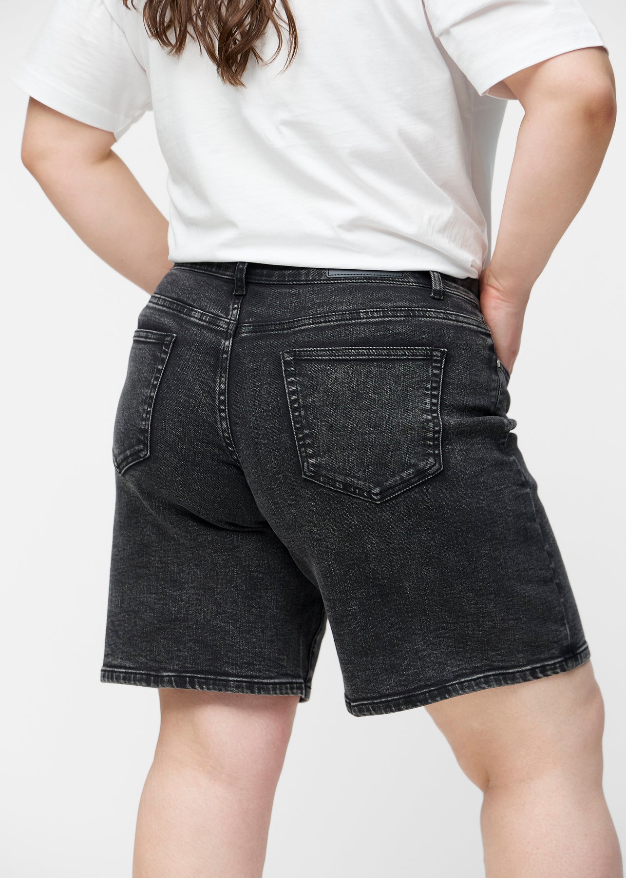 Løse, mørkegrå denim shorts i farven Shadows set bagfra tæt på på plus-size model for at vise pasform og detaljer.