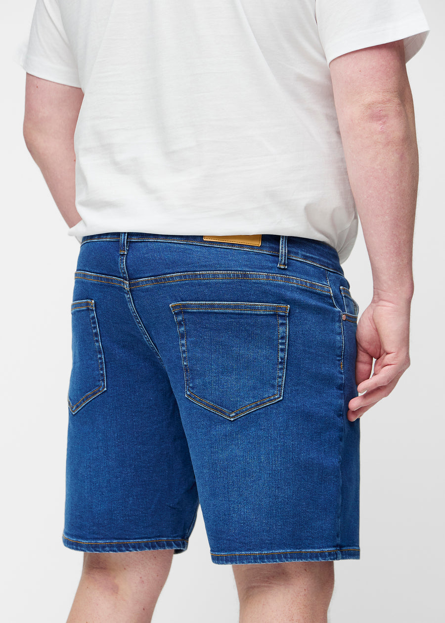 Dunkelblaue Denim-Shorts für Herren in der Farbe Oceans von hinten am Plus-Size-Modell gesehen.