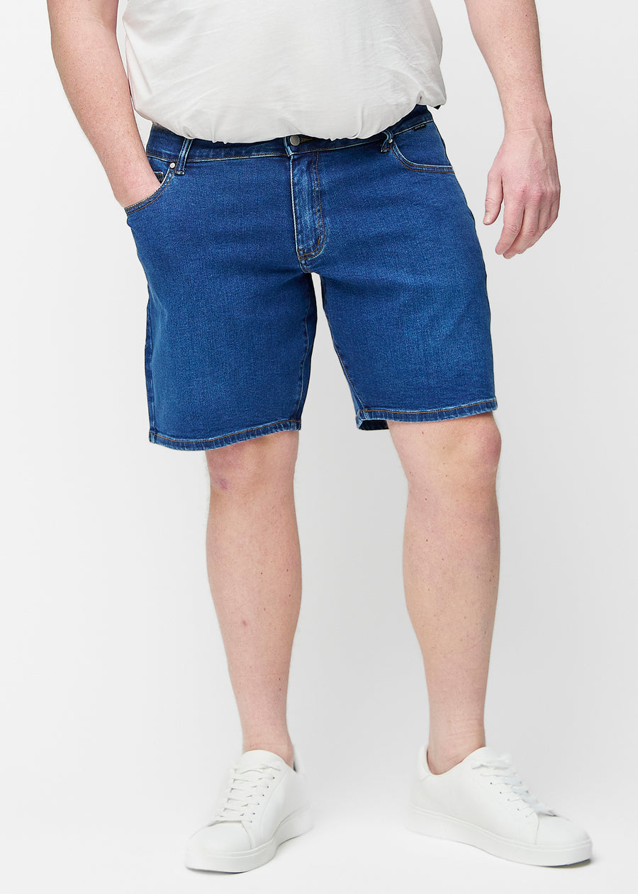 Ganzkörperbild eines Modells in dunkelblauen Denim-Shorts für Herren in der Farbe Oceans mit Regular-Passform.
