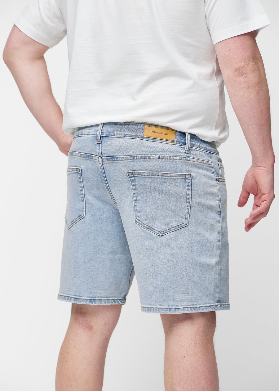 Hellblaue Denim-Shorts für Herren in der Farbe Waves von hinten am Plus-Size-Model gesehen, sodass die Länge bis knapp über das Knie sichtbar ist.