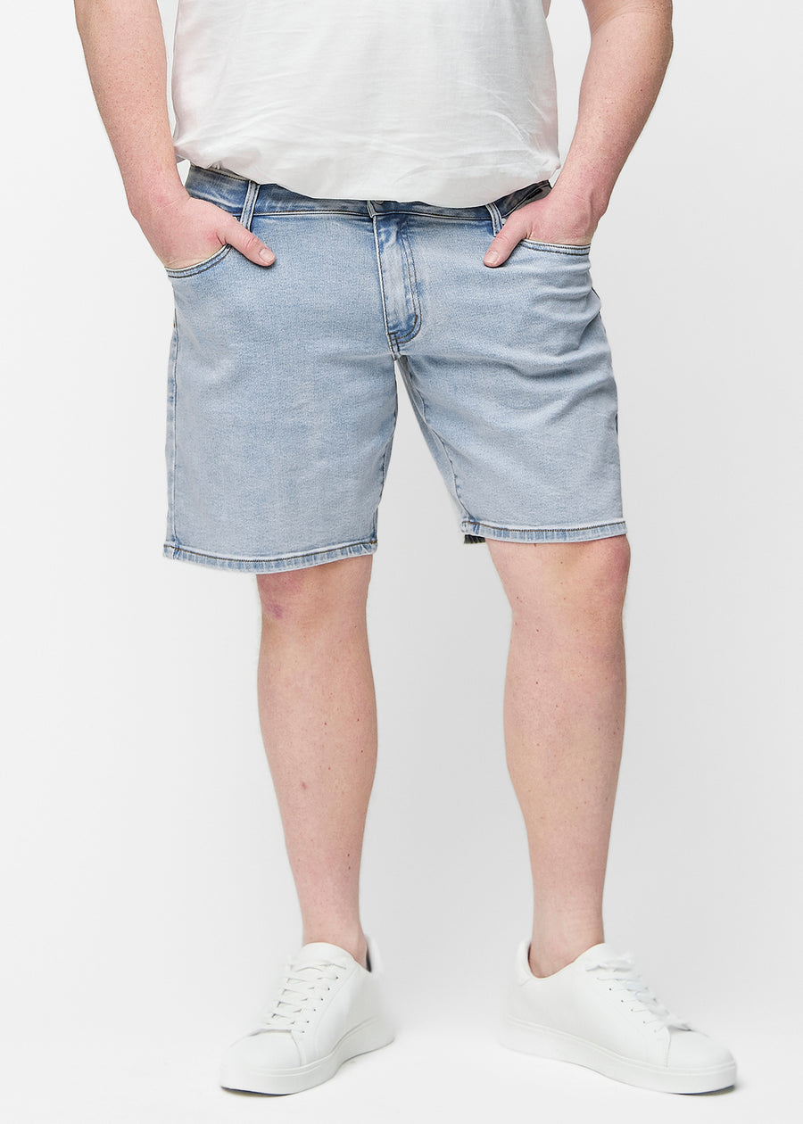 Hellblaue Denim-Shorts für Herren in der Farbe Waves mit Regular-Passform von vorne am Plus-Size-Model, die natürlich an der Hüfte sitzen und Luft um die Oberschenkel lassen.