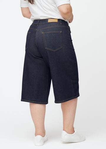 Tief dunkelblaue Denim-Capris für Damen in der Farbe Midnights von hinten auf einem Plus-Size-Model gesehen.
