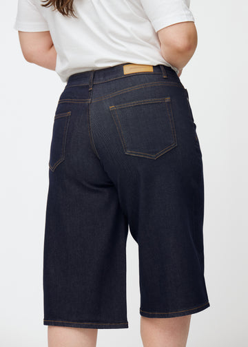 Tief dunkelblaue Denim-Capris für Damen in der Farbe Midnights von hinten nah auf einem Plus-Size-Model aufgenommen.