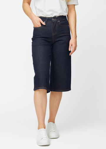 Tief dunkelblaue Denim-Capris für Damen in der Farbe Midnights mit Loose-Passform, die an der Hüfte sitzt und locker über Oberschenkel und Beine fällt, von vorne gesehen.