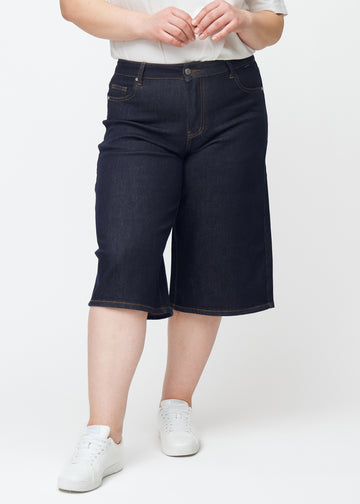 Tief dunkelblaue Denim-Capris für Damen in der Farbe Midnights mit Loose-Passform, von vorne auf einem Plus-Size-Model gesehen.