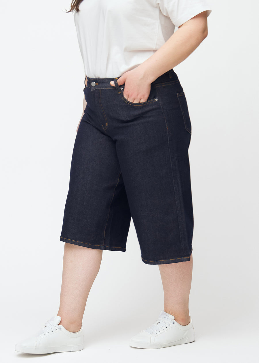Tief dunkelblaue Denim-Capris für Damen in der Farbe Midnights mit Loose-Passform, von der Seite auf einem Plus-Size-Model gesehen.
