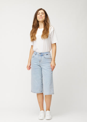 Ganzkörperaufnahme eines Models in lockeren, hellblauen Waves Denim-Capris, die bis knapp unter das Knie reichen.