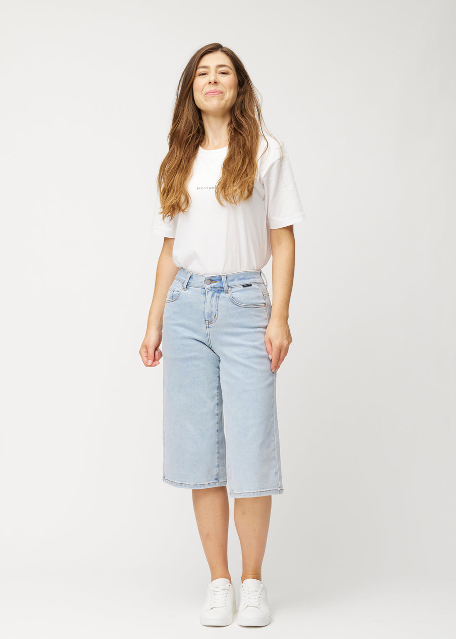 Ganzkörperaufnahme eines Models in lockeren, hellblauen Waves Denim-Capris, die bis knapp unter das Knie reichen.