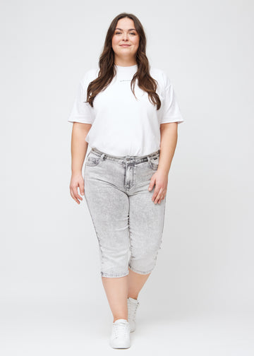 Ganzkörperbild eines Plus-Size-Models in hellgrauen Denim-regular-Capris.
