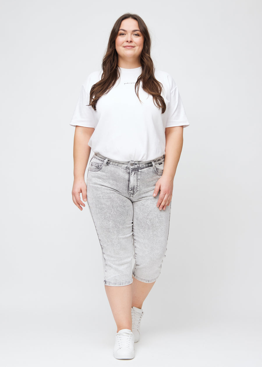 Ganzkörperbild eines Plus-Size-Models in hellgrauen Denim-regular-Capris.