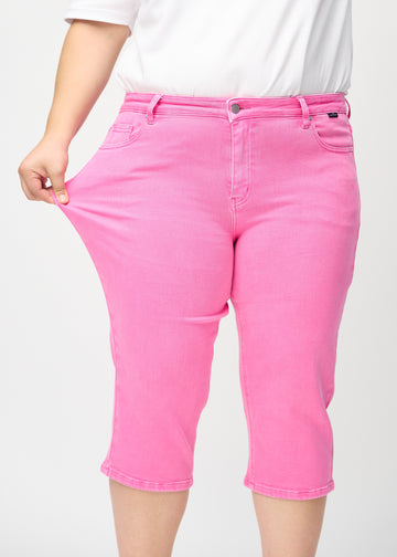 Das Plus-Size-Model zieht die Capris am Oberschenkel, um den Stretch zu zeigen.