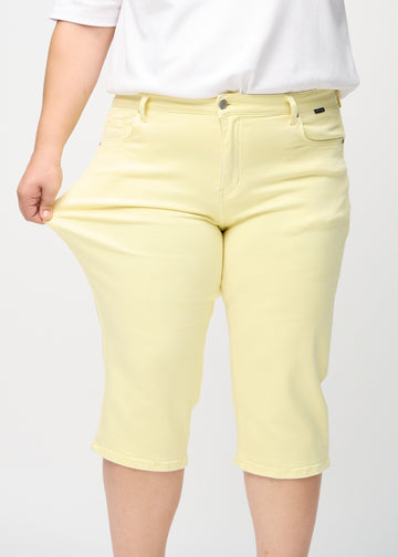 Das Plus-Size-Model zieht die Capris am Oberschenkel, um den Stretch zu zeigen.