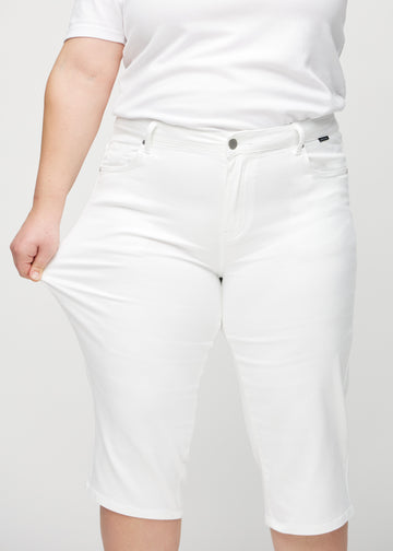 Das Plus-Size-Model zieht die Capris am Oberschenkel auseinander, um den Stretch zu zeigen.
