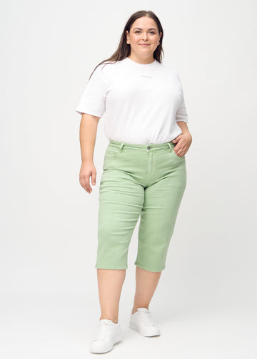 Ganzkörperbild eines Plus-Size-Models in hellgrünen regular Capris.