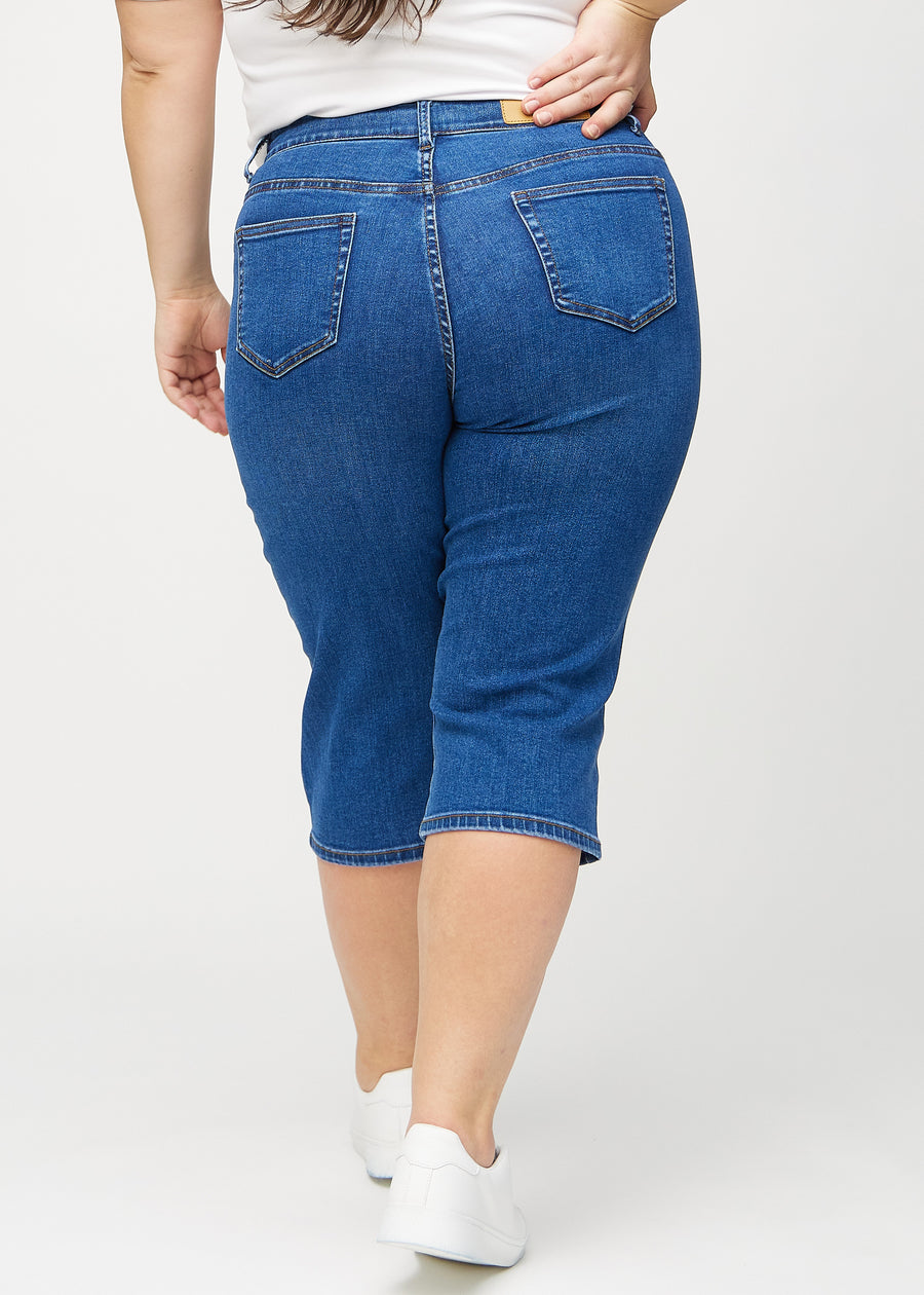 Dunkelblaue Denim-regular-Capris von hinten an einem Plus-Size-Model gesehen, sodass man das gesamte Produkt sehen kann.