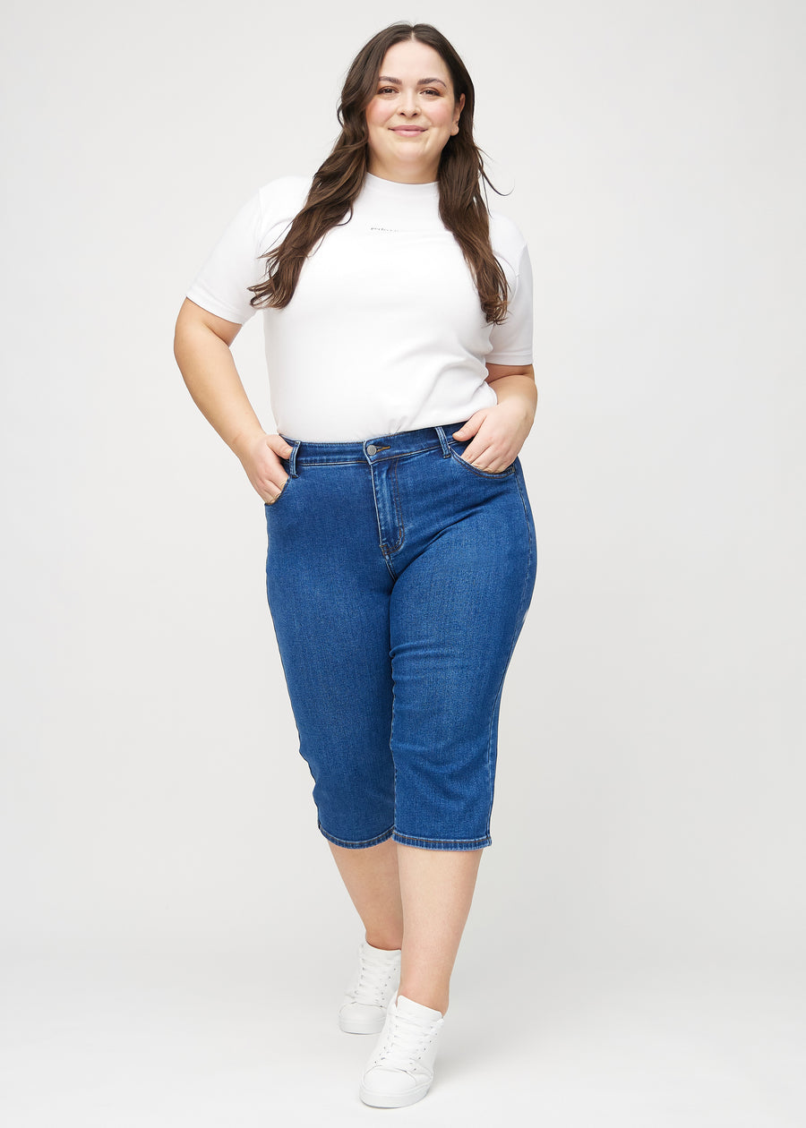 Ganzkörperbild eines Plus-Size-Models in dunkelblauen Denim-regular-Capris.