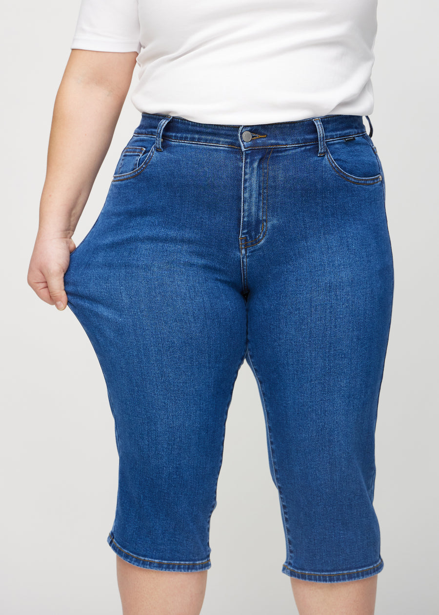 Das Plus-Size-Model zieht die Capris am Oberschenkel, um den Stretch zu zeigen.
