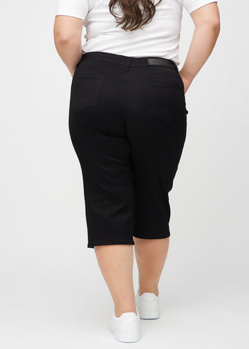 Schwarze regular Capris von hinten an einem Plus-Size-Model gesehen, sodass man das gesamte Produkt sehen kann.