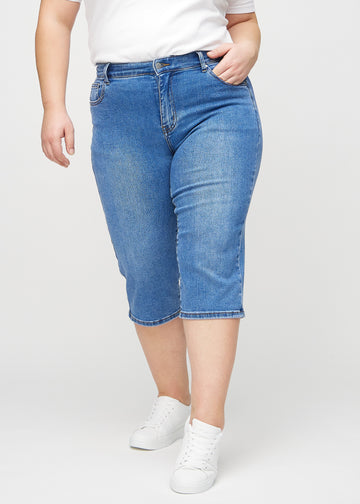 Denim-regular-Capris, Modellname Rivers, die eng am Bein anliegen und direkt unter dem Knie enden, an einem Plus-Size-Model von vorne gesehen.
