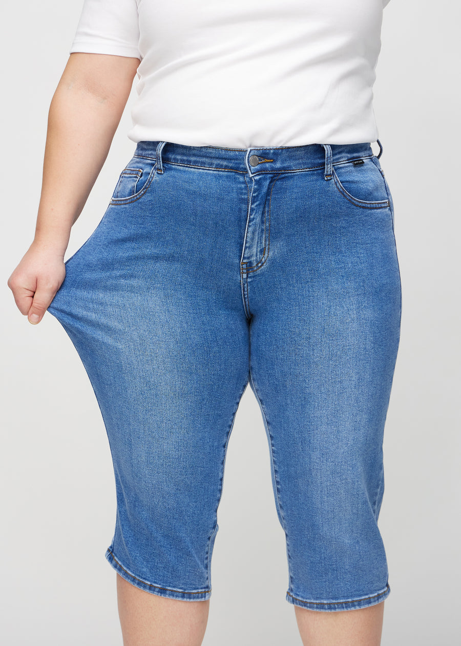 Das Plus-Size-Model zieht die Capris am Oberschenkel auseinander, um den Stretch zu zeigen.