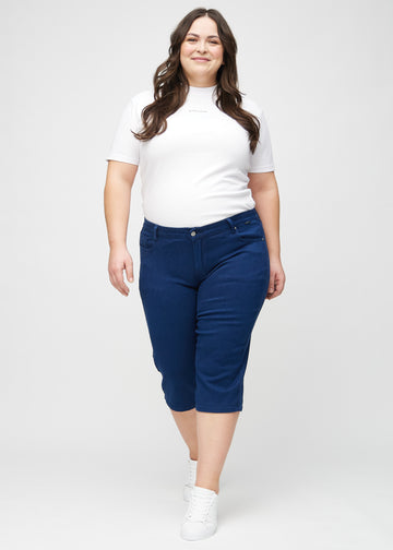 Ganzkörperbild eines Plus-Size-Models in dunkelblauen regular Capris.