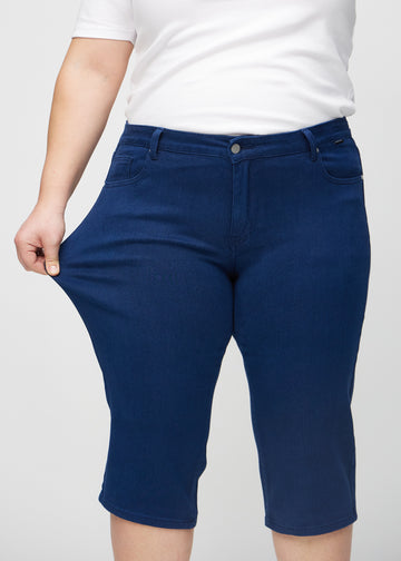 Das Plus-Size-Model zieht die Capris am Oberschenkel, um den Stretch zu zeigen.