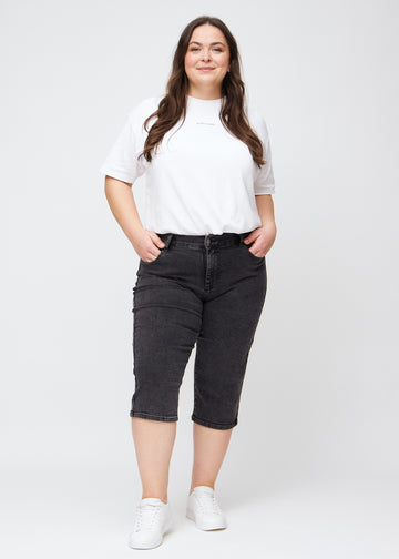 Ganzkörperbild eines Plus-Size-Models in dunkelgrauen Denim-regular-Capris.