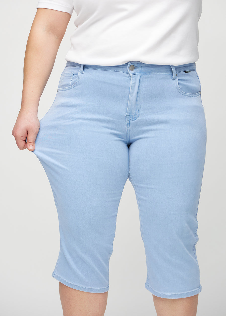 Das Plus-Size-Model zieht die Capris am Oberschenkel auseinander, um den Stretch zu zeigen.