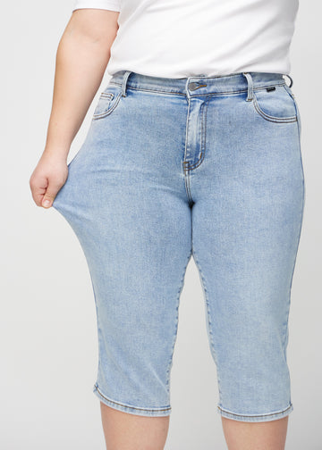 Das Plus-Size-Model zieht die Capris am Oberschenkel auseinander, um den Stretch zu zeigen.