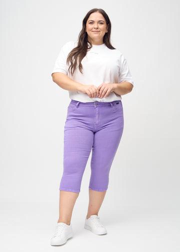 Ganzkörperbild eines Plus-Size-Models in lila skinny Capris.