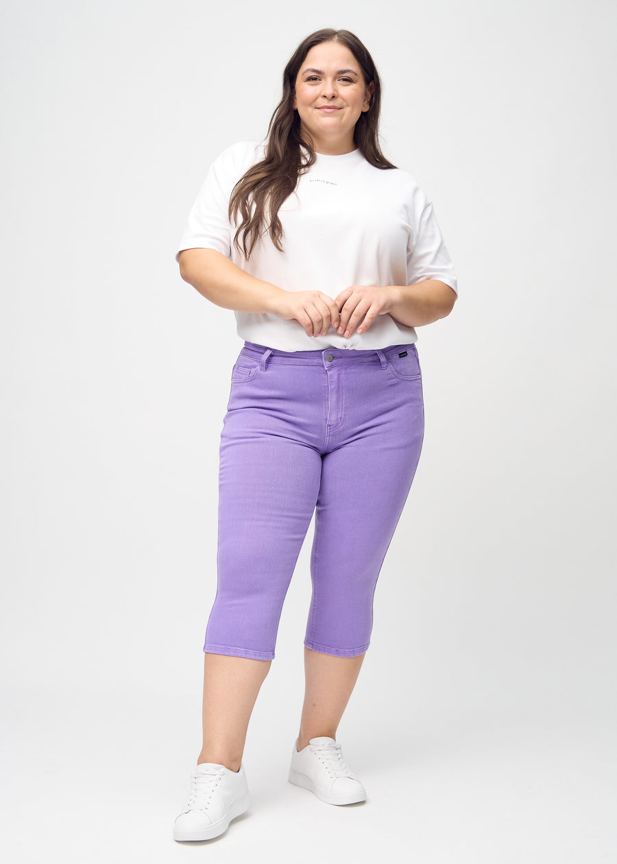 Ganzkörperbild eines Plus-Size-Models in lila skinny Capris.