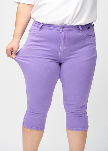 Das Plus-Size-Model zieht die Capris am Oberschenkel auseinander, um den Stretch zu zeigen.