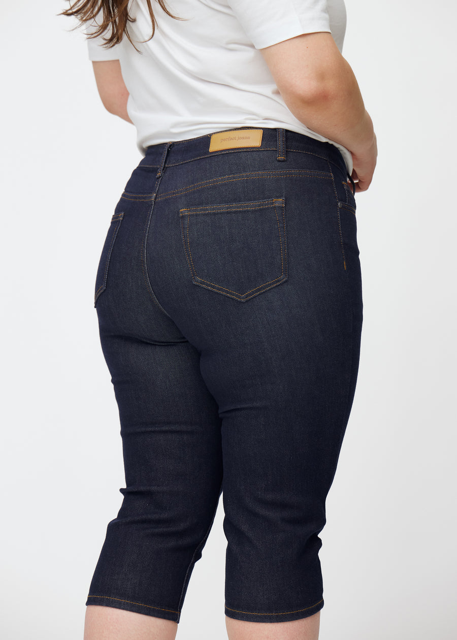 Tief dunkelblaue Denim-Capris für Damen in der Farbe Midnights von hinten nah auf einem Plus-Size-Model aufgenommen.